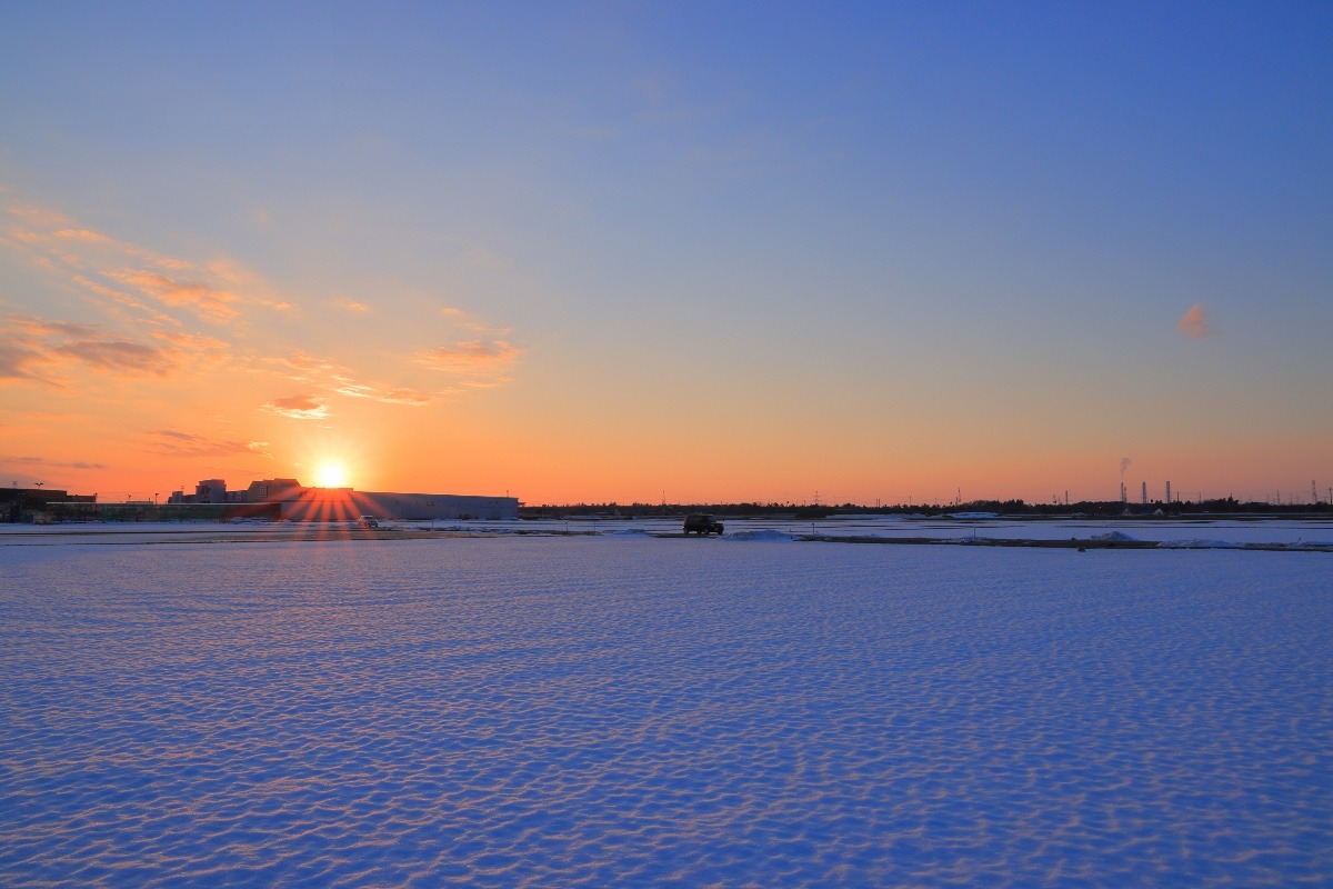 雪の田んぼに広がる夕日